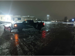 Plow truck clearing a commercial parking area after heavy snowfall.